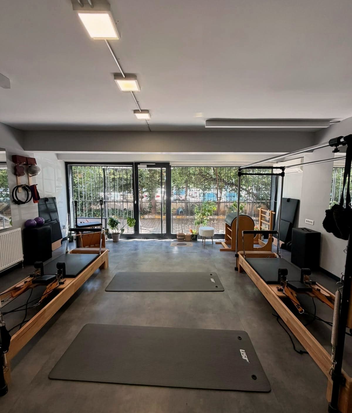 Pol Pilates Studio ana salonu — ahşap reformerlar ve cam cepheden gelen gün ışığı