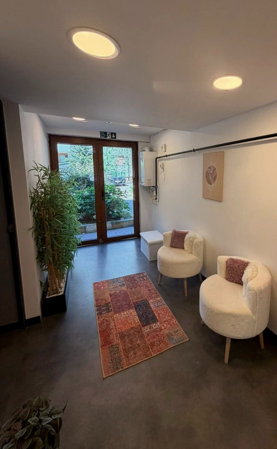Bekleme alanı — bouclé koltuklar, kilim ve bitkiler